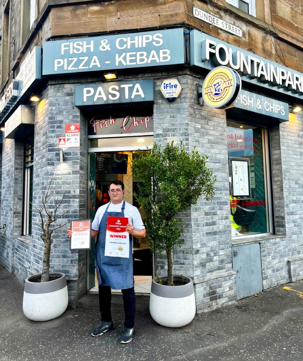  the Owner of the Shop Holding the Award at Fountain Park Fry 
Takeaway in Edinburgh